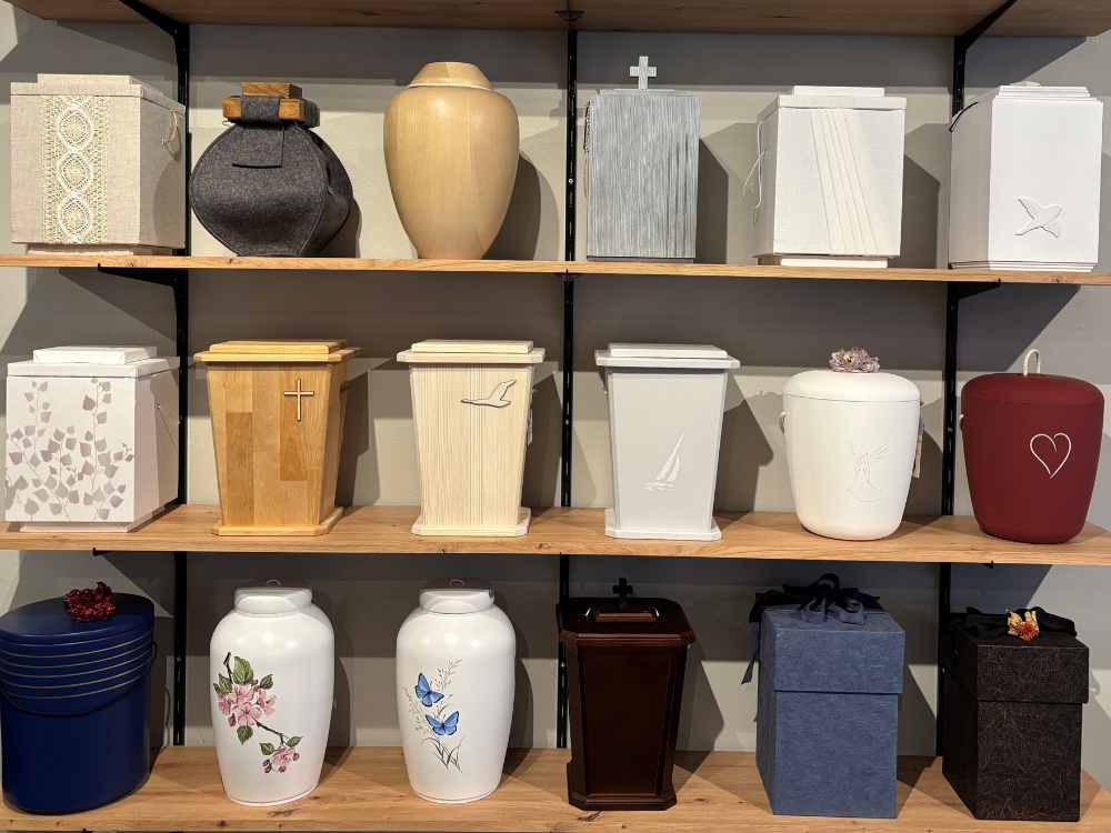 Vaaleita ja värillisiä uurnia kolmella hyllyllä.