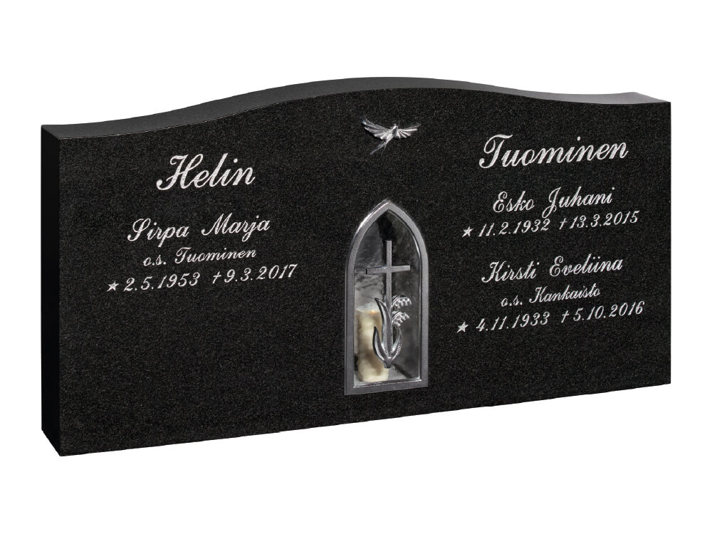 Malata ja leveä, koristeellinen musta hautakivi, jonka keskelle on upotettu kromin värinen kielokoristeinen kynttilälyhty ja yläosassa lintukoriste. Hautauspalvelu Kaiho - Hautakivet
