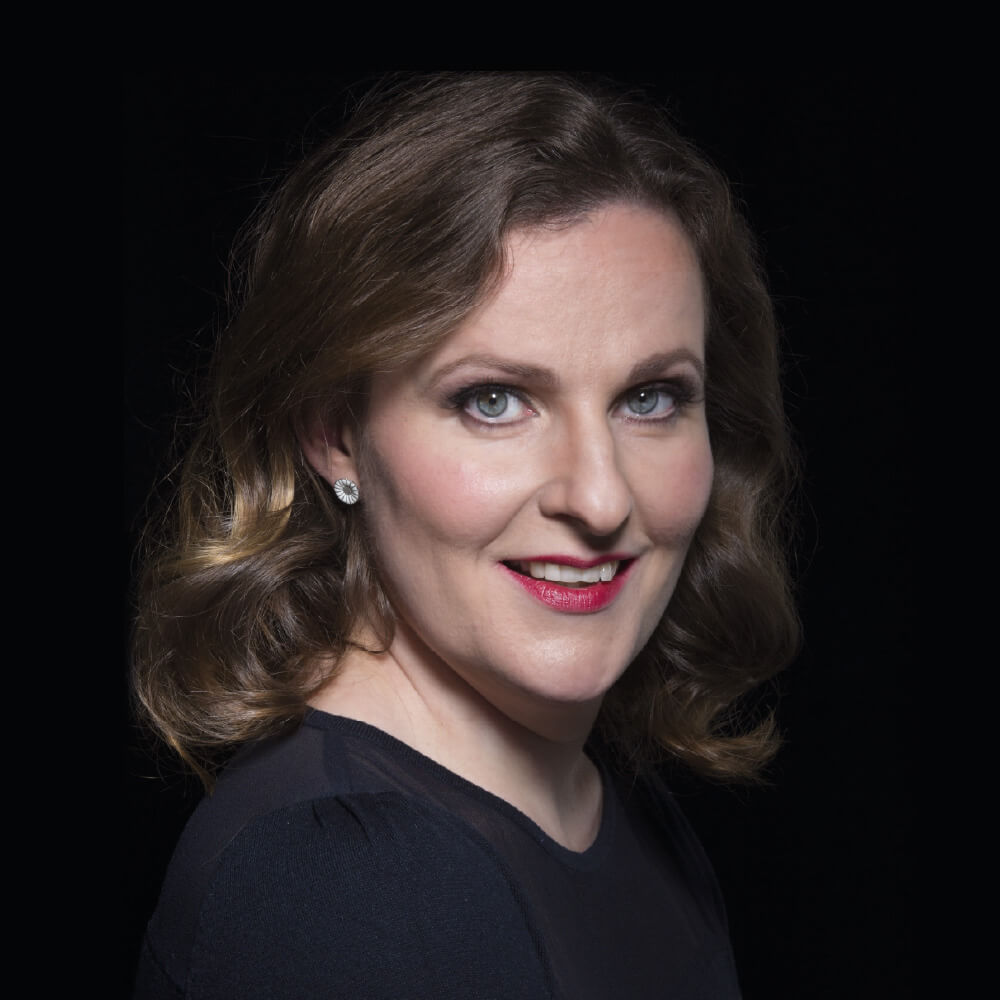 Kaunispiirteinen nainen, Hedvig Paulig, jolla on loivat kiharat hiukset, katsoo suoraan kameraan. Hautauspalvelu Kaiho Oy - Musiikki ja Puhe kuva