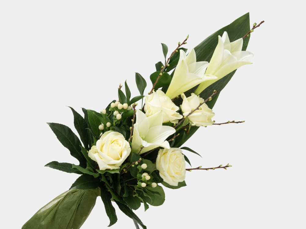 Kimpussa valkoisia liljoja ja ruusuja, oksia joissa on silmuja ja valkoista marjaoksaa. Hautauspalvelu Kaiho Oy - Hautajaiskukat kuva