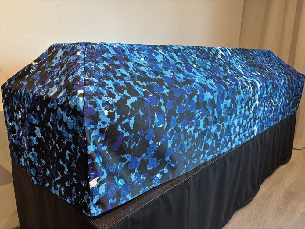 Sini-mustankirjava arkkuliina peittää arkkua mustaksi verhoillun korokkeen päällä. Hautaspalvelu Kaiho Oy - Tietoa Kaihosta - Vastuulliset vaihtoehdot kuva